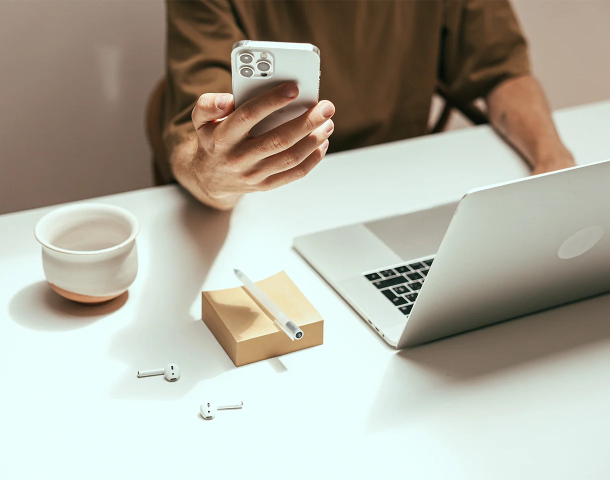Person holding phone while using computer